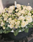 Bouquet of white flowers with a bottle of champagne on a reflective surface.