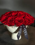 Bouquet of red roses on a mannequin head with a 'GRAVEL' ribbon against a dark background