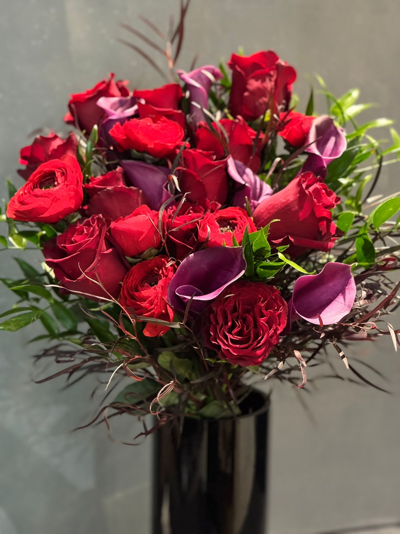 Red Freedom Roses, Purple Calla Lillies, Red Ranunculus, Agonis, and Italian Rucus Bouquet - Nationwide Shipping