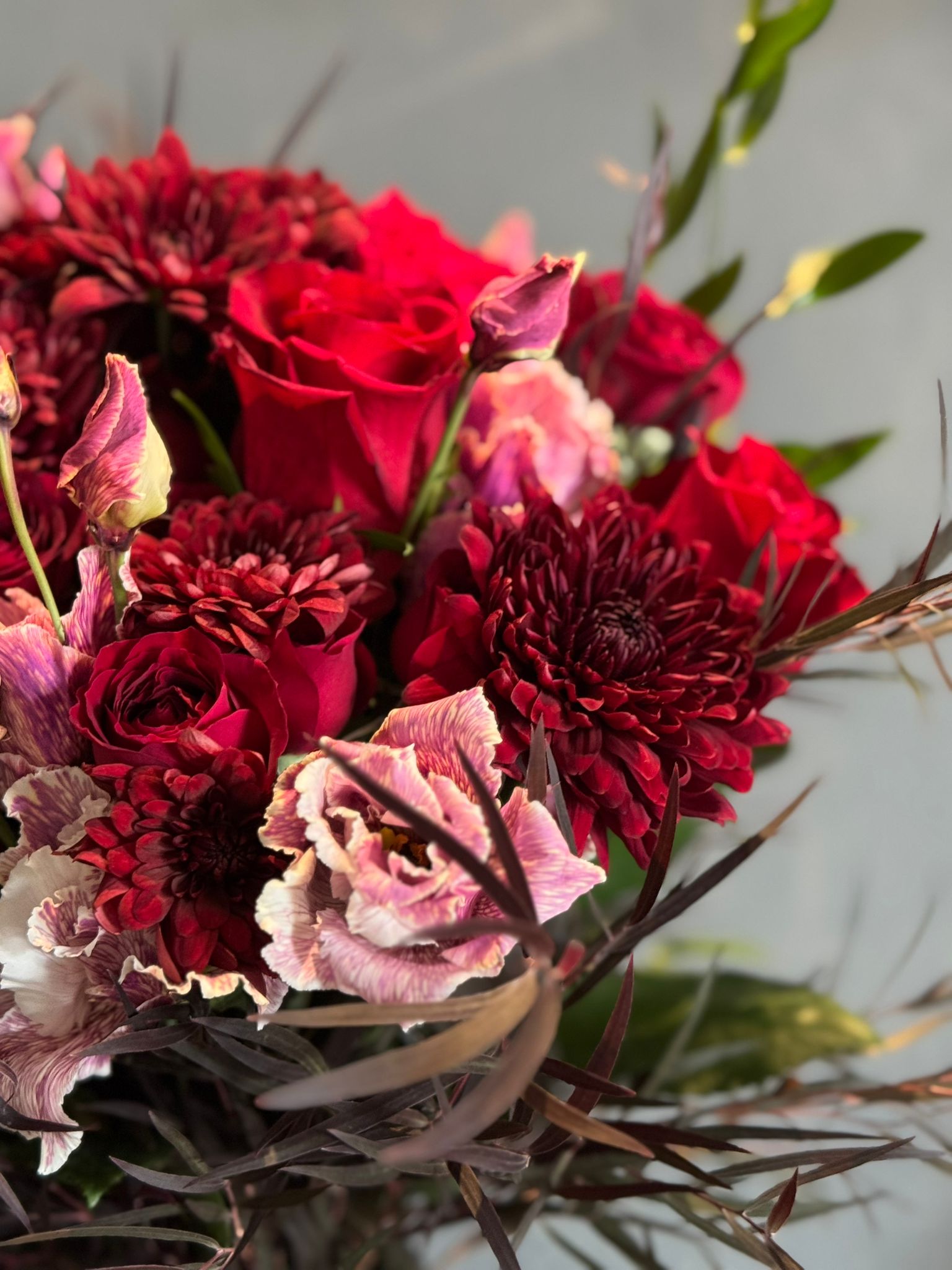 Red Roses, Lisianthus, Red Chrysanthemums, Agonis, and Italian Ruscus Hand Bouquet