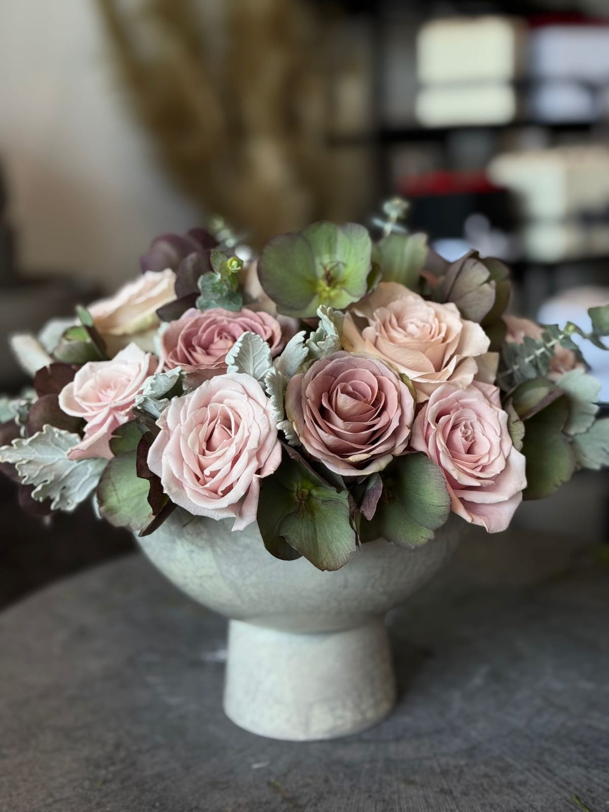 Bouquet of pink roses and greenery in a white vase on a blurred background