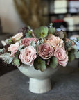Bouquet of pink roses and greenery in a white vase on a blurred background