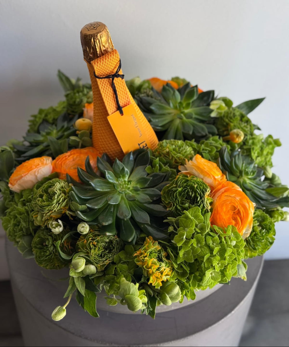 Decorative arrangement with a bottle of champagne made from flowers and greenery.