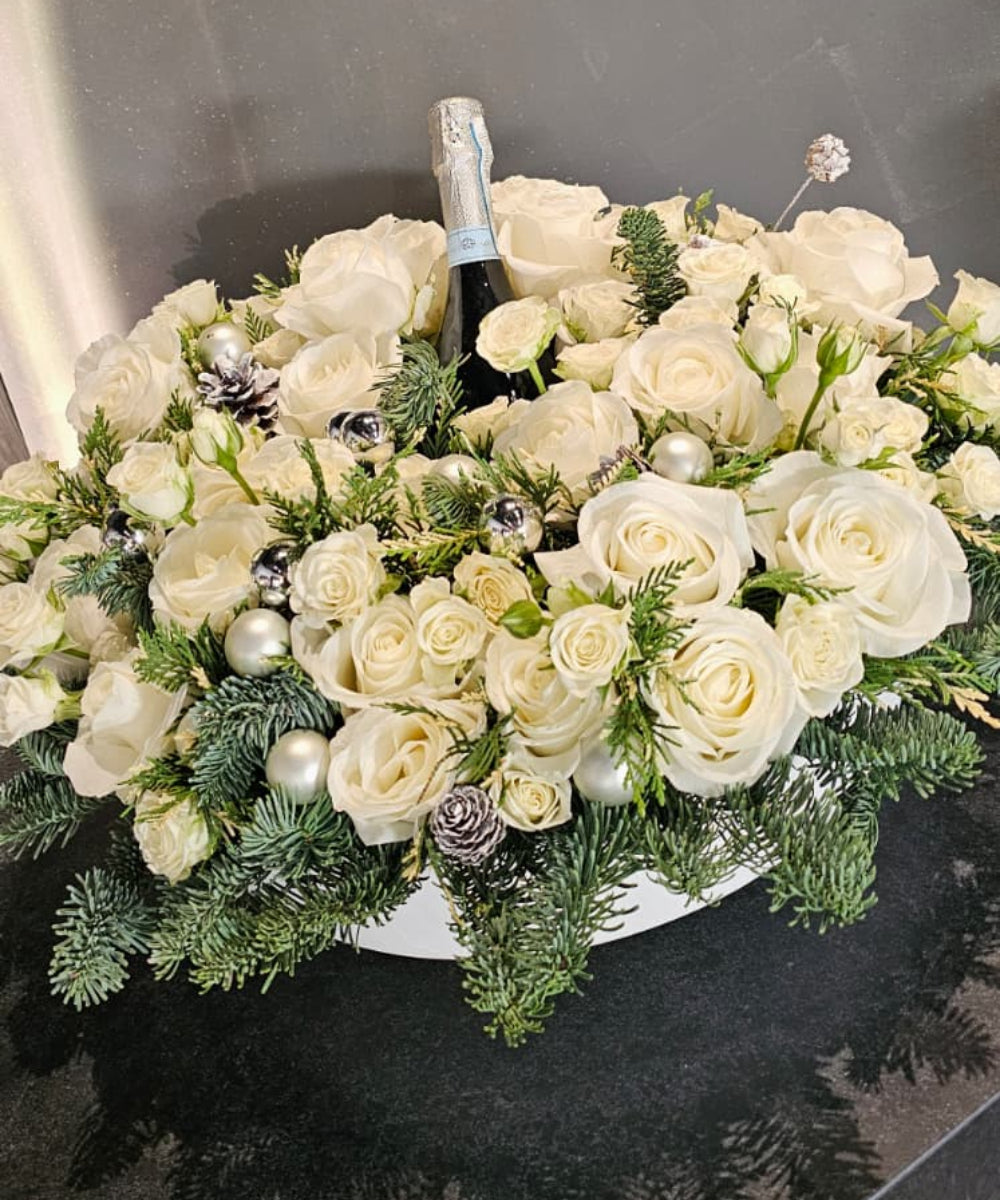 Bouquet of white flowers with a bottle of champagne on a black surface, with 'GRAVEL' branding in the background.