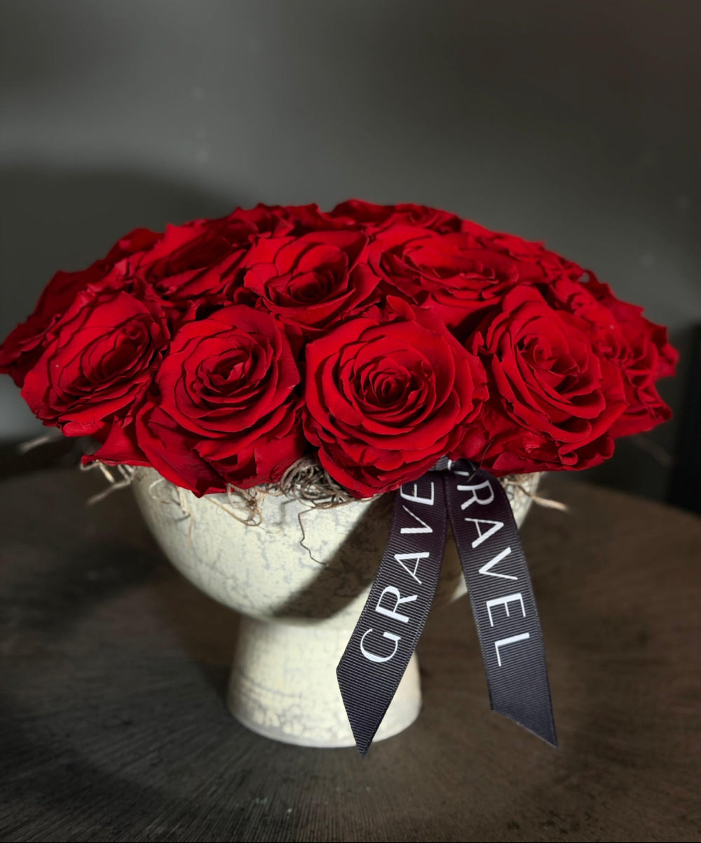 Bouquet of red roses on a mannequin head with a 'GRAVEL' ribbon against a dark background