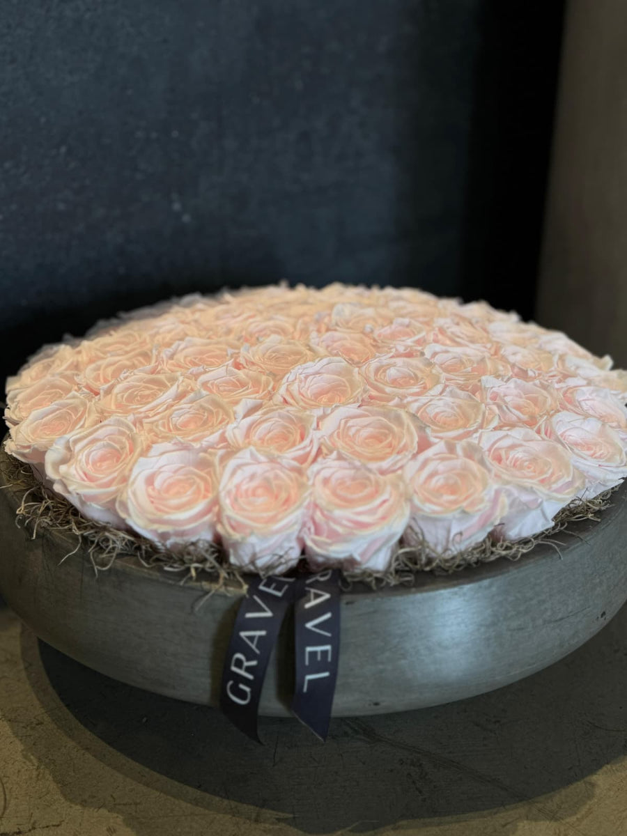 Round arrangement of peach roses in a gray box with &#39;GRAVEL&#39; ribbon.